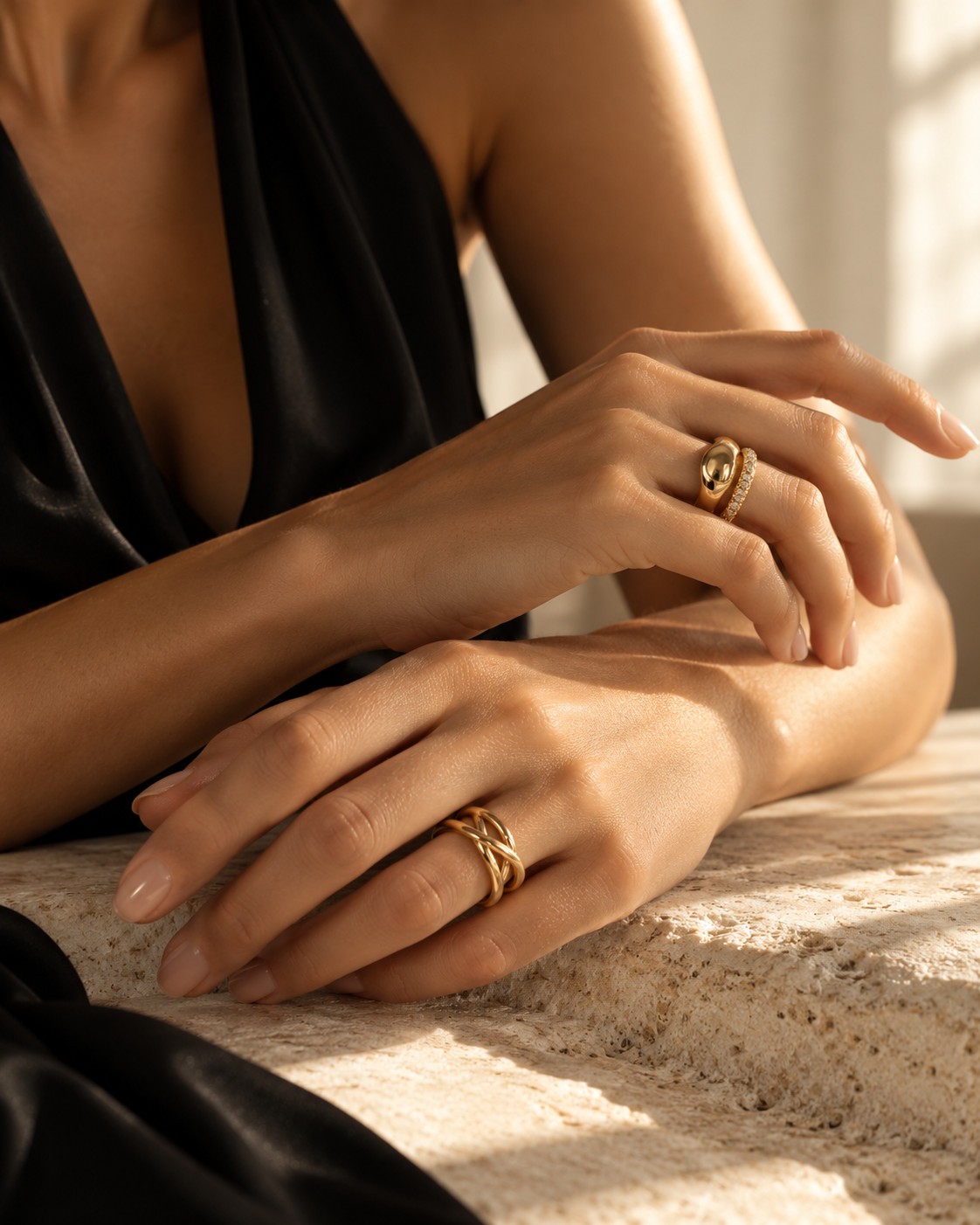 Goldene Ringe an Händen auf einer hellen Steinfläche.